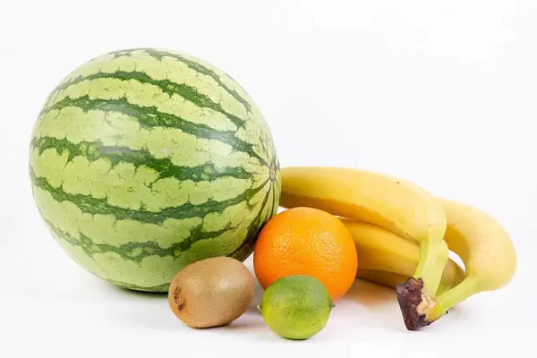 Verschiedene Früchte wie Wassermelone, Kiwi, Orange, Limette und Bananen, vor weißem Hintergrund