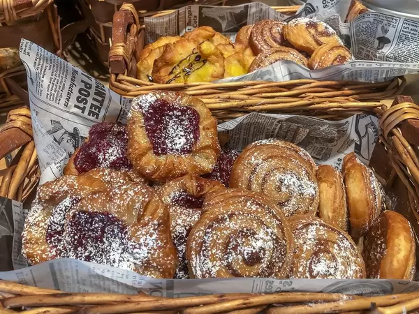 Verschiedenes Gebäck mit Marmeladenfüllung und Puderzucker, in Holzkörben, mit Zeitung ausgelegt