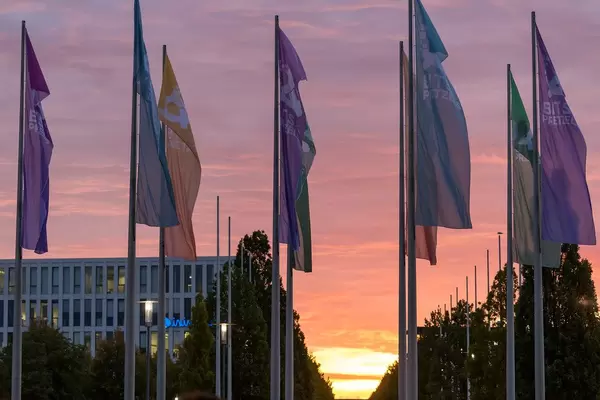 Verschiedenfarbige Bits&Pretzels Fahnen wehen im Wind mit Sonnenuntergang im Hintergrund