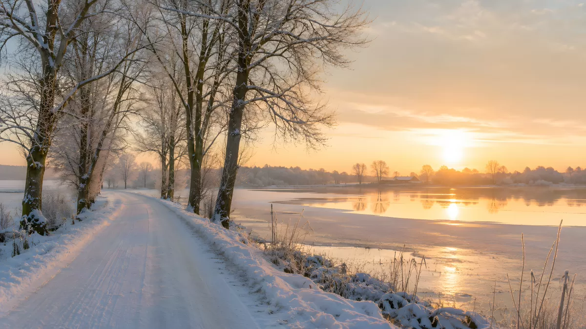 Verschneite Landstraße an gefrorenem See im Sonnenaufgang