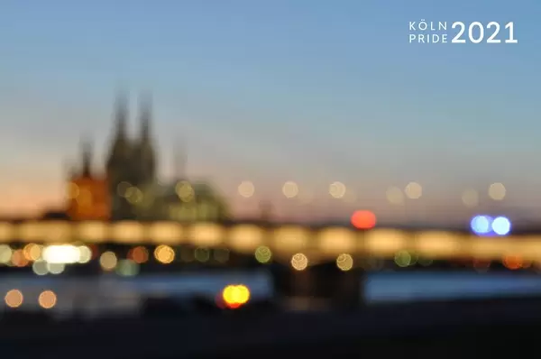 Verschwommenes Hintergrundbild mit Lichtern und Kölner Dom, neben dem Bildtitel Köln Pride 2021, um den CSD zu feiern