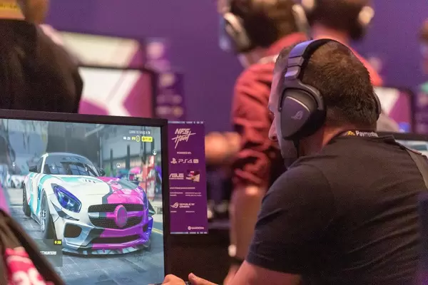 Video gamer with headphones test the new Need For Speed "NFS Heat" game on Playstation 4 at Gamescom