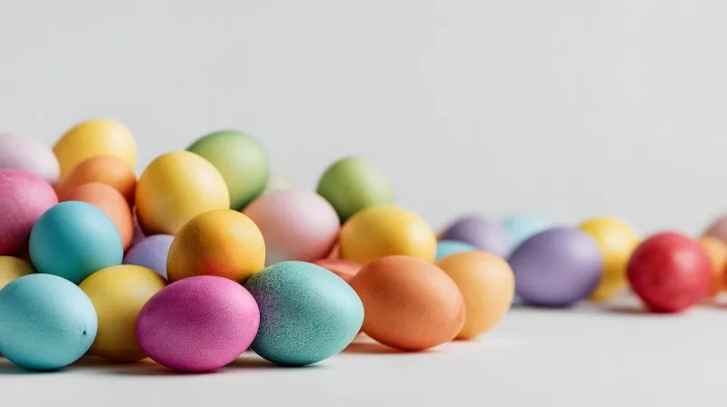 Viele bunte Ostereier liegen auf weißem Hintergrund nebeneinander