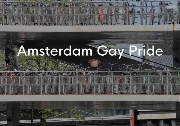 Viele Fahrräder auf Brückenübergängen geparkt, neben dem LGBTQ Festivalname Amsterdam Gay Pride