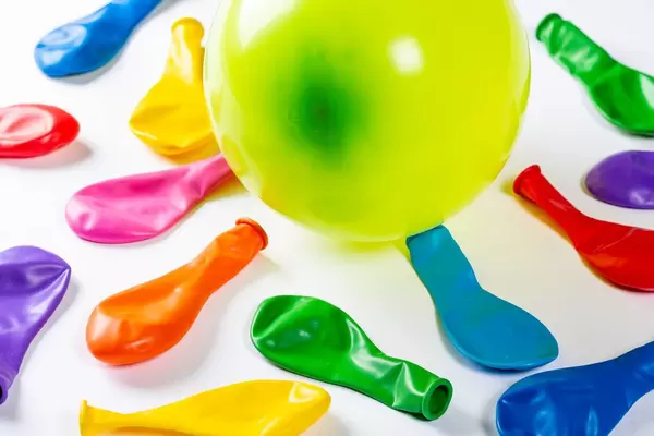 Viele nicht aufgeblasene und ein mit Luft gefüllter Ballon auf weißem Hintergrund