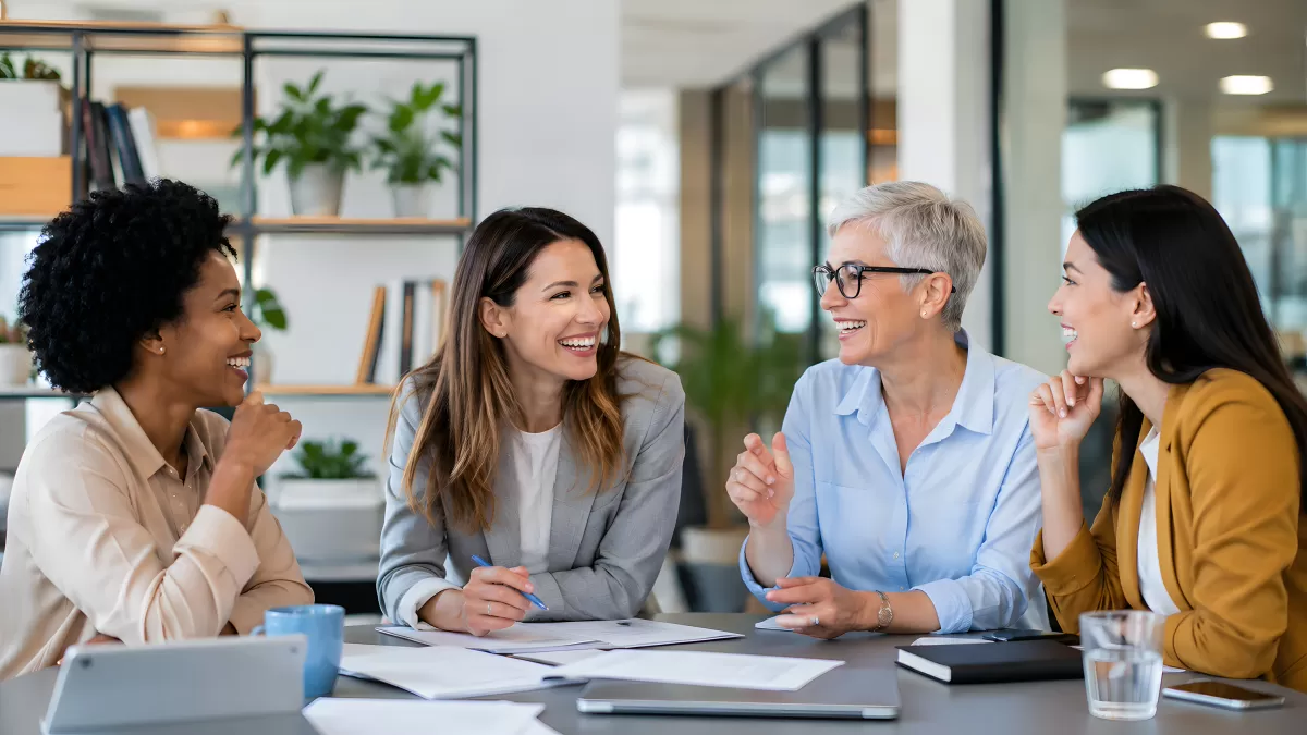 Vier Frauen im Büro-Meeting lachen gemeinsam
