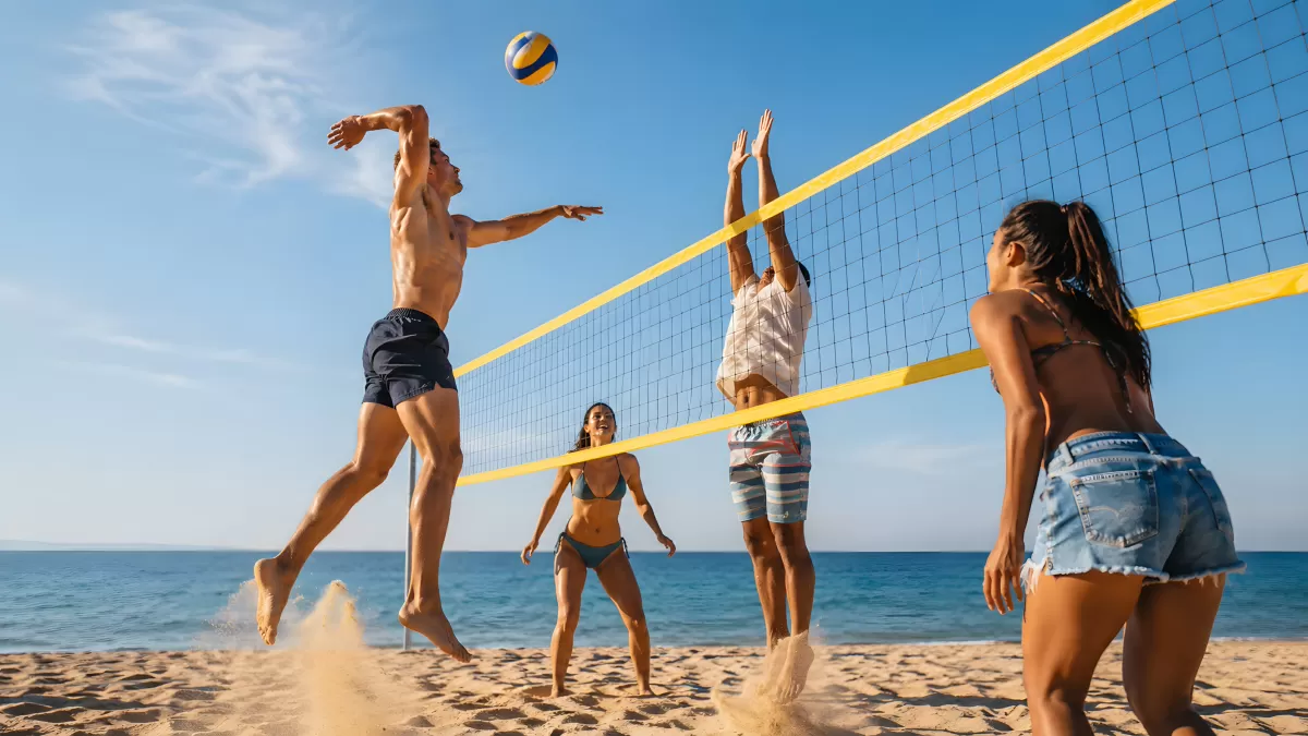 Vier Freunde spielen Beachvolleyball am Meer