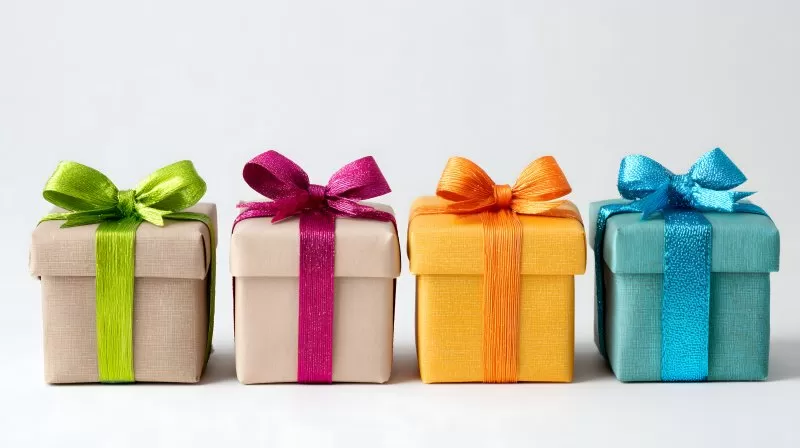 Vier Geschenke in braunem Papier mit Kordel auf Holzhintergrund