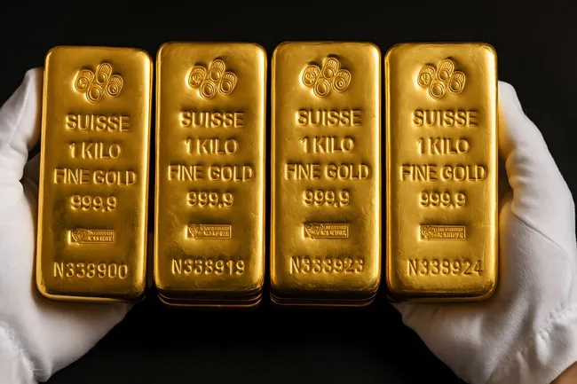 Vier goldene Barren mit Suisse-Aufdruck auf schwarzem Hintergrund
