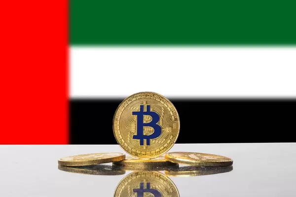 Vier goldene Münzen der Kryptowährung Bitcoin vor der Flagge der Vereinigten Arabischen Emirate