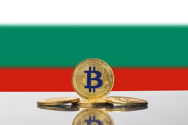 Vier Münzen der Kryptowährung Bitcoin drapiert vor der Flagge Bulgariens