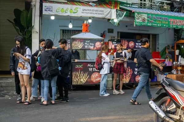 Vietnamese High School Students standing around Street Food Carts at Ho Thi Ky Flower Market in Ho Chi Minh City, Vietnam