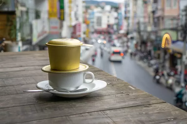 Vietnamese Hot Coffee with Traditional Filter on  a Wooden Table and a View of Dalat, Vietnam in the Background