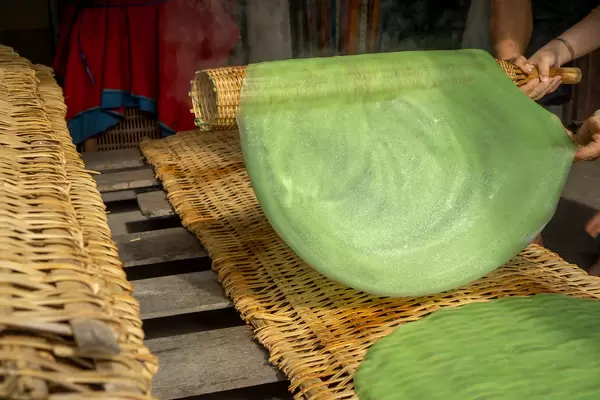Vietnamese Vegetable Handmade Rice Paper is being placed on a Bamboo Rack to dry in the Sun at a Local Workshop in the Mekong Delta in Vietnam