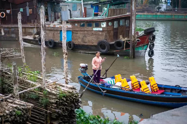 Vietnamese Woman picking up Tourists for a Cai Rang Floating Market Private Tour with a Wooden Motorboat with Life Vests in Can Tho, Vietnam