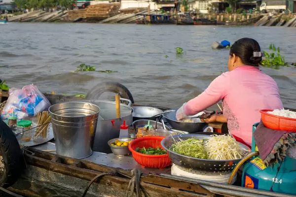 Vietnamese Woman selling Hu Tieu Soup from a Noodle Soup Kitchen on a Boat at Cai Rang Floating Market in Can Tho, Vietnam