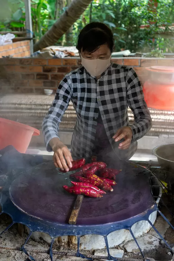 Vietnamese Woman steaming Sweet Potatoes to prepare handmade Rice Paper at a Workshop in the Mekong Delta in Vietnam