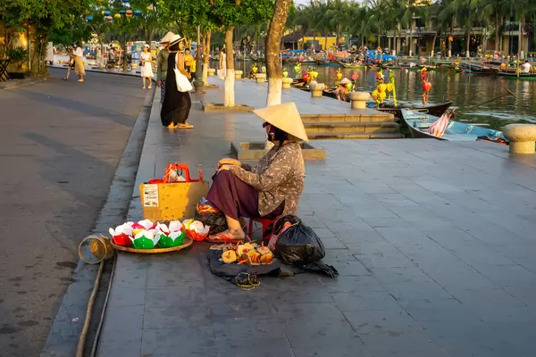 Vietnamese Woman with a Conical Hat selling Floating Lantern Candles on the Pedestrian Street along the Thu Bon River in Hoi An, Vietnam