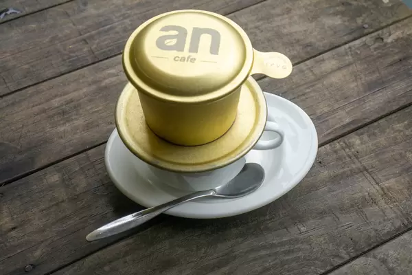 Vietnamesicher Kaffee mit Löffel und Untertasse auf einem Holztisch Draufsicht