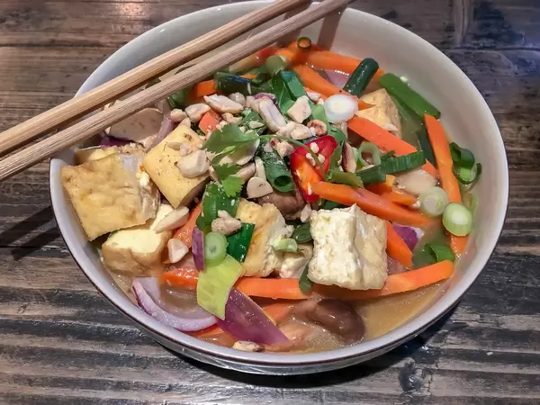 Vietnamesisches Gemüse-Gericht mit Zwiebeln, Paprika und Karotte in wießer Schale im Nahaufnahme