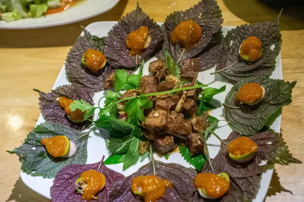 Vietnamesisches Gericht mit gebratenem Rindfleisch, Kräutern und Kumquat Sauce von oben fotografier