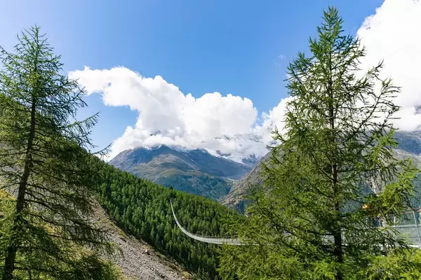 View at the longest pedestrian suspension bridge disappearing into the distance underneath the cloud covered mountains