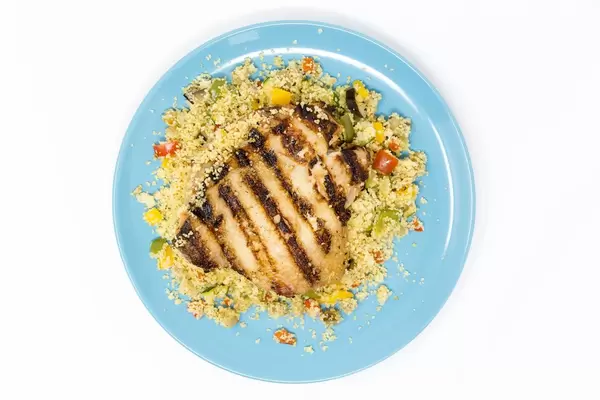 View from above on plate with chicken arabic grilled with vegetable couscous with razel hanout dip