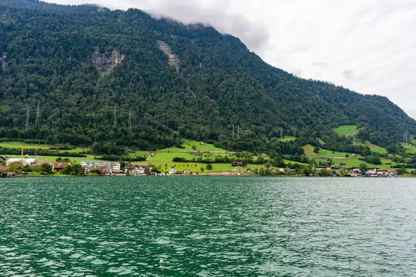 View of a Swiss village on the shore of the lake with hills disappearing into the clouds in the background