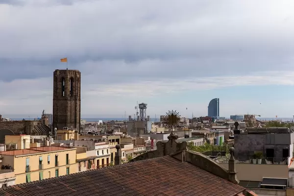 View over roofs to the gothic church tower "Basílica de Santa Maria del Pi" and Hotel W at the Platja de Sant Sebastià beach in Barcelona, Spain