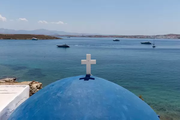 View over the blue dome with white cross of St. John's of Deti Church, to motorboats in the Mediterranean Sea at Paros, Greece