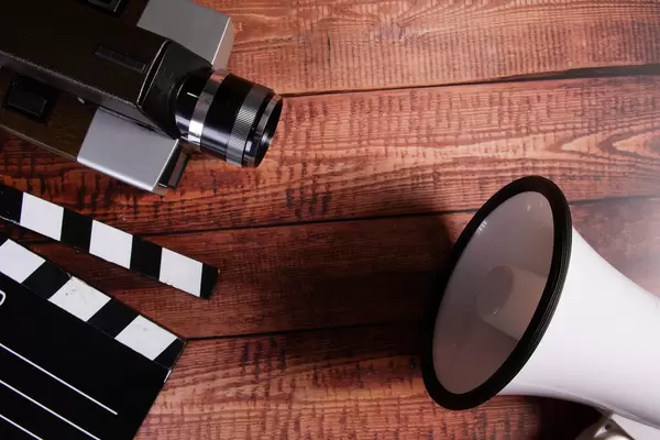 Vintage camera, movie clapper and megaphone on wooden blackground