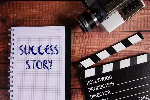 Vintage camera, movie clapper and notebook with Success Story text