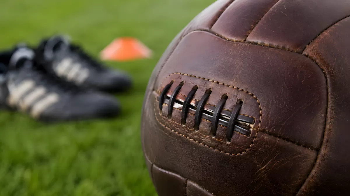 Vintage Lederball auf Rasen mit Fußballschuhen