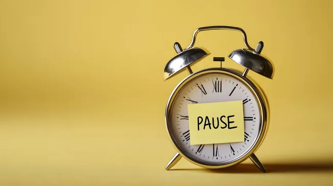 Vintage Wecker mit 'Pause'-Notiz auf gelbem Hintergrund