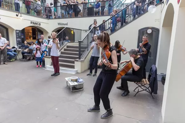 Violin and cello players playing in front of a tea bar in London