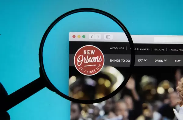 Visit New Orleans logo on a computer screen with a magnifying glass