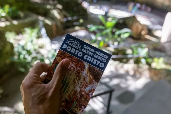 Visitor holding the leaflet of the Caves of Porto Cristo in his hand. Tourist attraction on Majorca