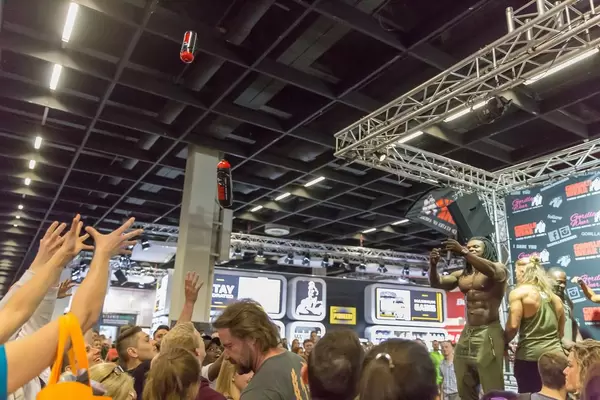 Visitors catching free sport plastic bottles thrown by Kevin Osazee - FIBO Cologne 2018