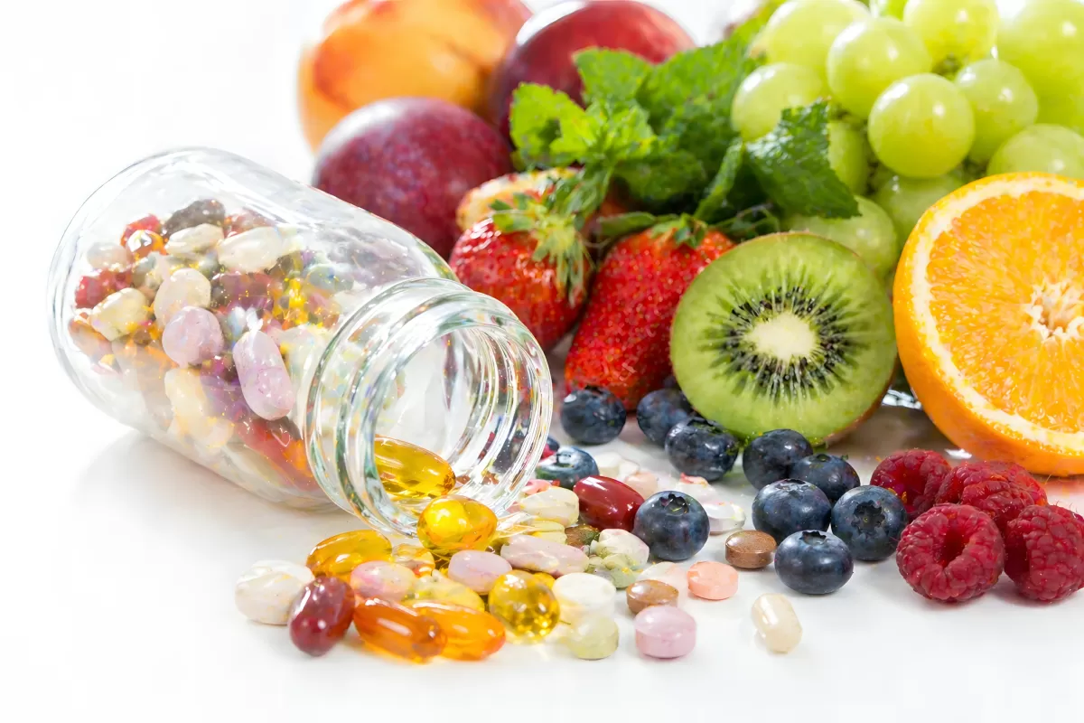 Vitaminpräparate und frische Früchte im Vergleich