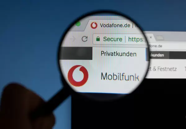 Vodafone-Logo am PC-Monitor, durch eine Lupe fotografiert