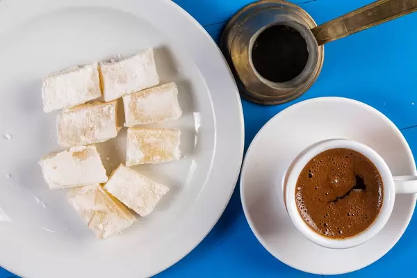 Vogelperspektive zeigt eine gefüllte Tasse Kaffee, Kupferkaraffe und Lokum, Turkish Delight
