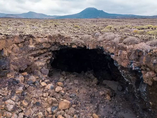 Volcanic cave in front of mountain range / Vulkanhˆhle vor Gebirgszug