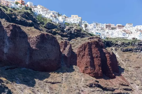 Volcanic rock formations below the white village of Oia on the Greek island Santorini