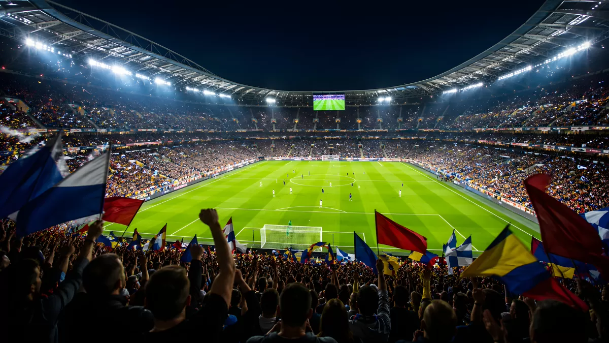 Vollbesetztes Fußballstadion bei Nacht mit Fahnen
