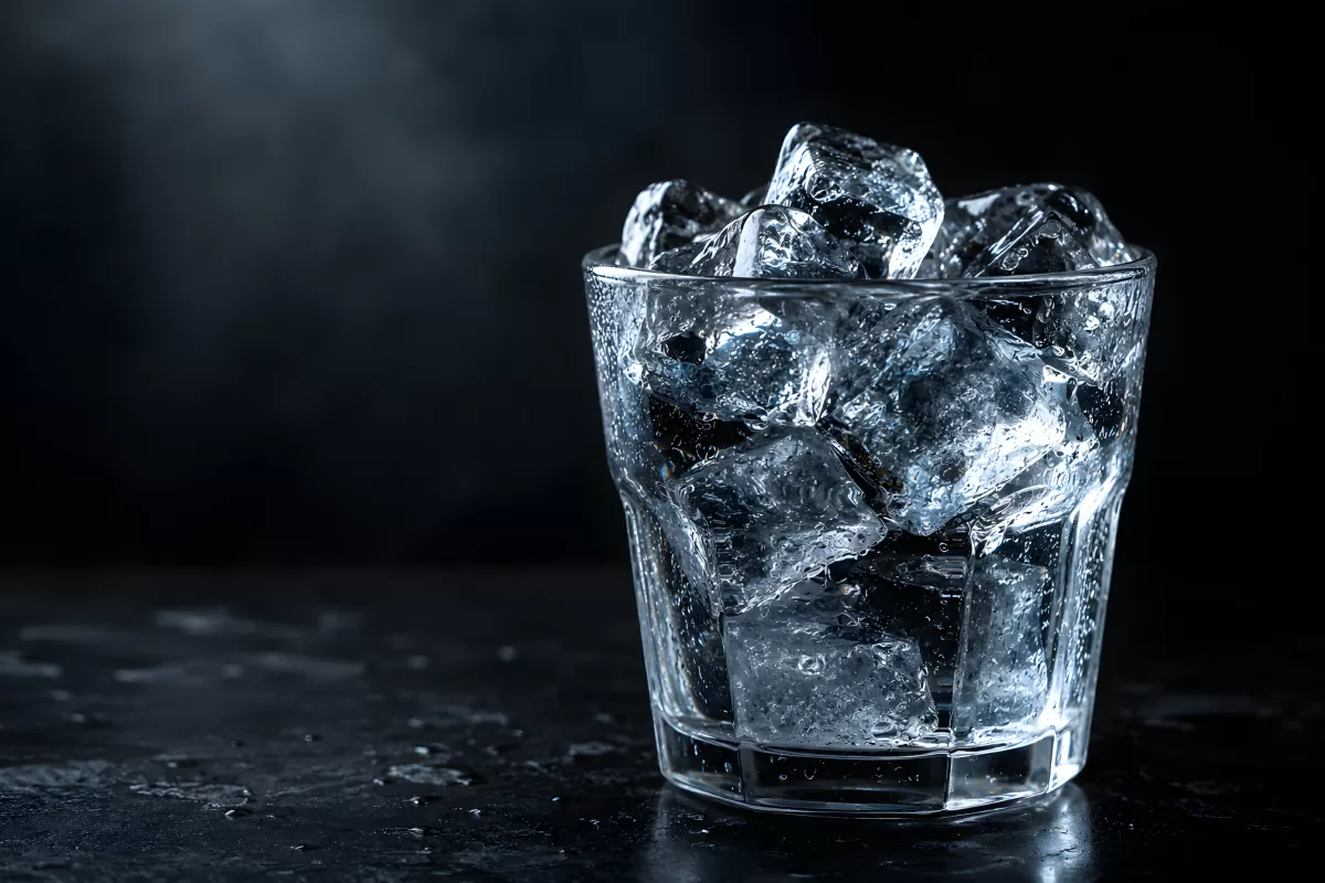 Volles Glas mit Eiswürfeln vor dunklem Hintergrund