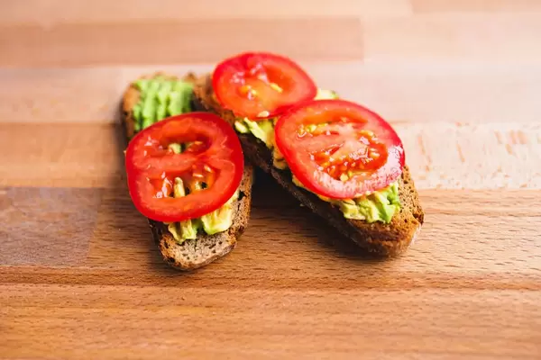 Vollkorn-Brotscheibe mit Avocadoaufstrich und frischen Tomatenscheiben in Nahaufnahme