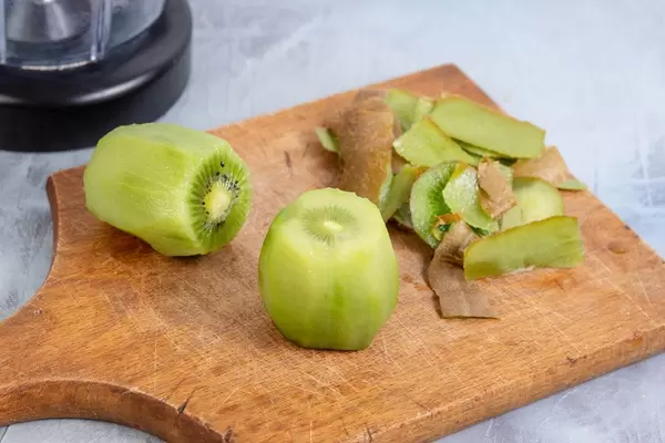 Vorbereitung von Kiwi-Saft, geschälte Kiwi auf Holzbrett vor Mixer