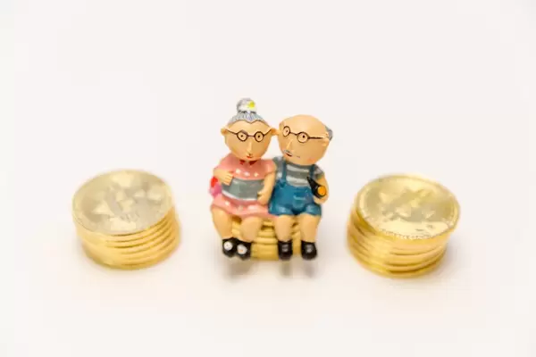 Vorsorgeplan für das Alter - Altes Paar sitzt auf Geldmünzen als Symbol for Altersvorsorge