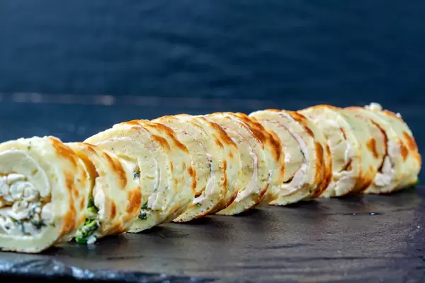 Vorspeise aus in Rollen geschnittener Omelette lecker gefüllt mit Hüttenkäse und Kräutern in Reihe