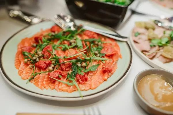 Vorspeise mit Lachs, Paprika, Kapern und Rucola auf einem Teller Nahaufnahme